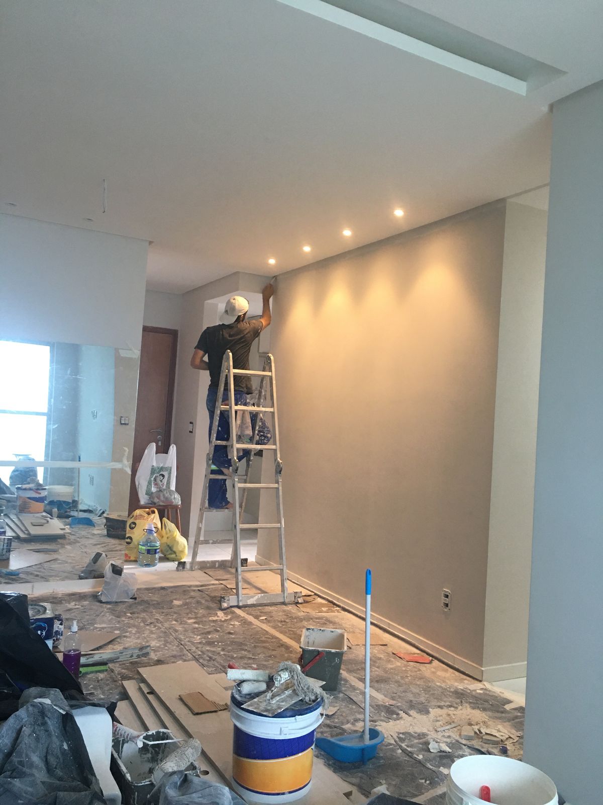 Profissional a pintar uma parede com o pavimento protegido